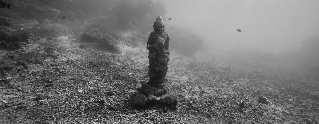 A photograph of an underwater statue to illustrate the short story "Do Something Amazing Today" by Gareth Durasow, published in issue 49 of Neon